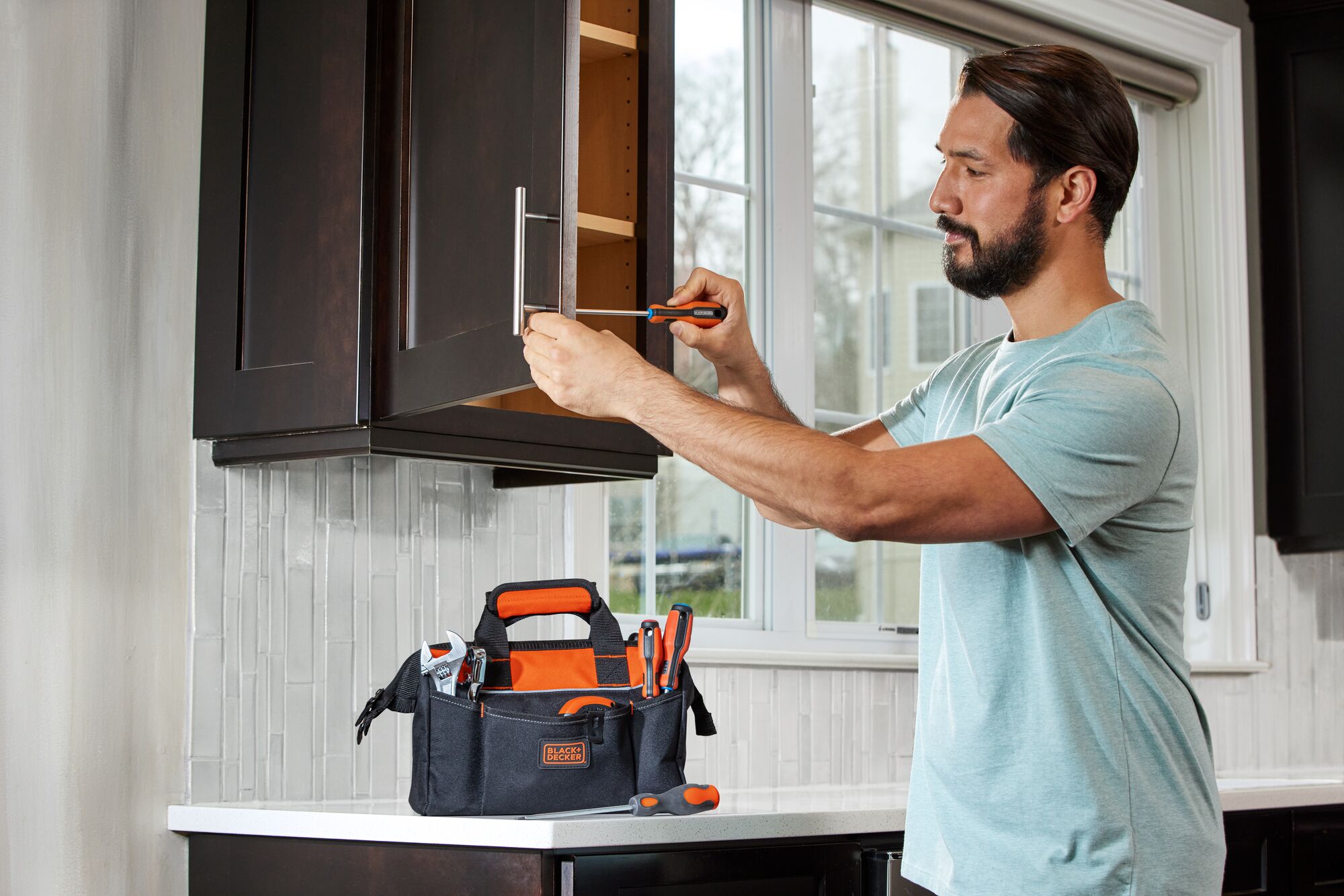 Tool Bag 12 inch being used by person to store his tools while he works on fixing a cabinet handle.